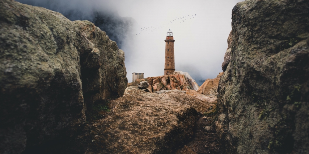 lighthouse on cliff near rock mountain