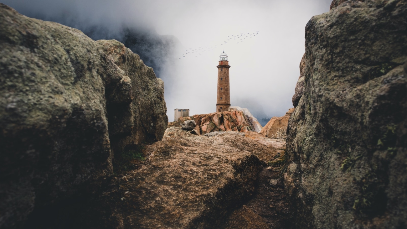 lighthouse on cliff near rock mountain