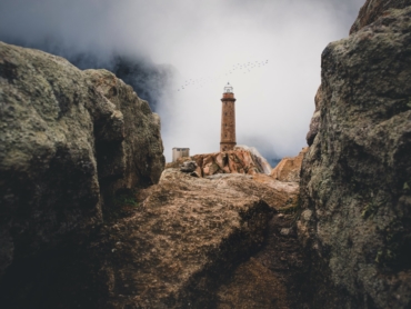 lighthouse on cliff near rock mountain