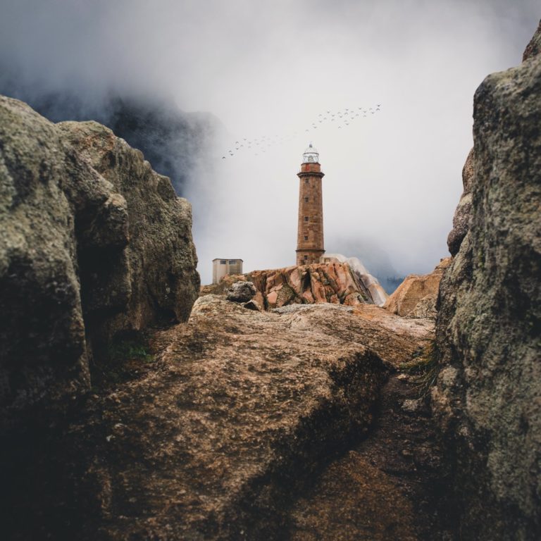 lighthouse on cliff near rock mountain